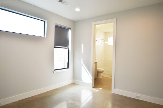 unfurnished bedroom featuring concrete flooring and ensuite bathroom