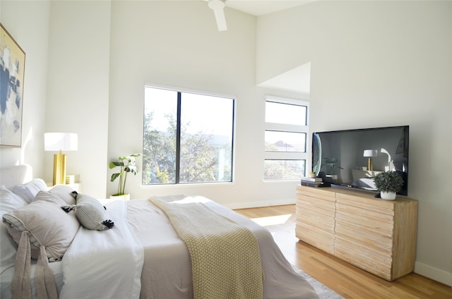 bedroom featuring a towering ceiling and hardwood / wood-style flooring