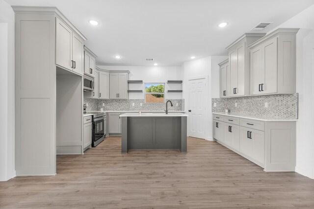 kitchen featuring light hardwood / wood-style flooring, appliances with stainless steel finishes, gray cabinetry, and a kitchen island with sink