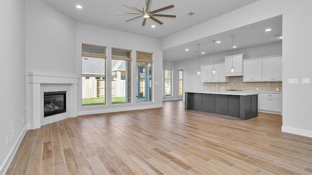 unfurnished living room with ceiling fan and light wood-type flooring