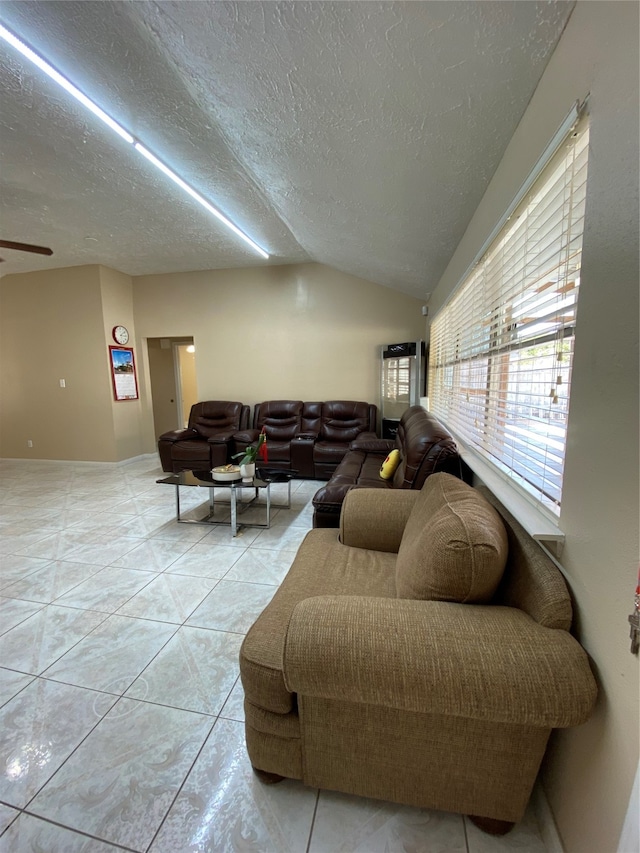 living room featuring lofted ceiling, a textured ceiling, ceiling fan, and light tile patterned floors