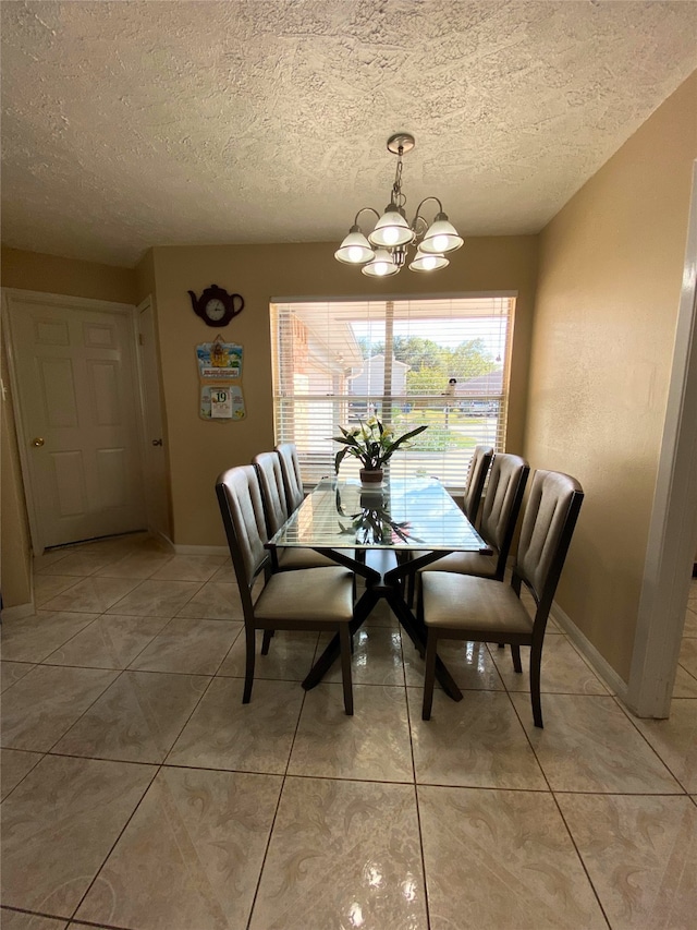 tiled dining area with an inviting chandelier and a textured ceiling