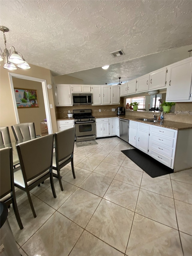 kitchen featuring white cabinetry, stainless steel appliances, a textured ceiling, and light tile patterned floors