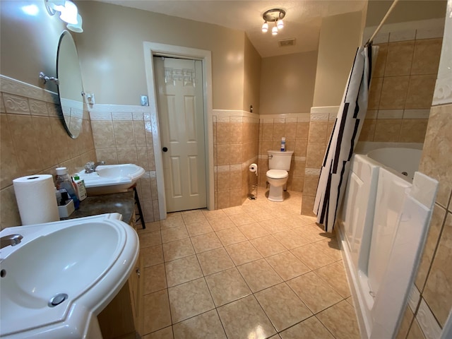 bathroom with tile walls, vanity, toilet, and tile patterned flooring