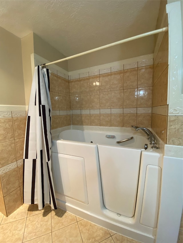 bathroom with a textured ceiling, tile walls, and tile patterned flooring