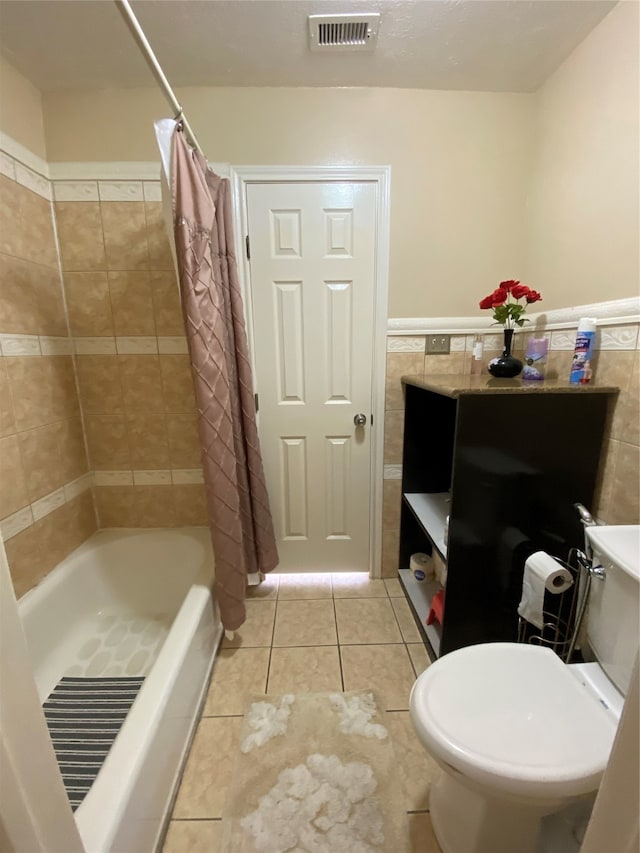 bathroom with toilet, shower / bath combo with shower curtain, tile patterned flooring, and tile walls