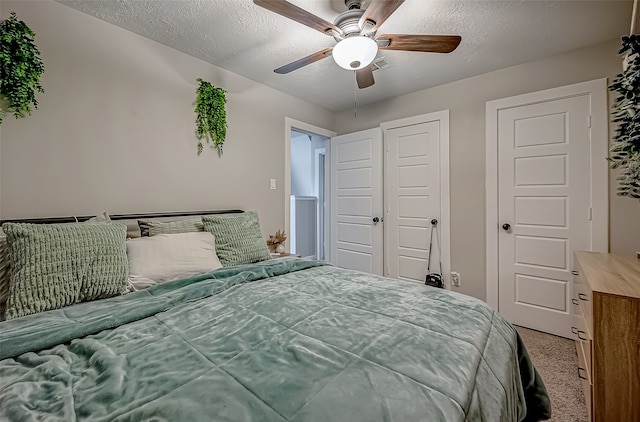 bedroom with ceiling fan, carpet flooring, and a textured ceiling