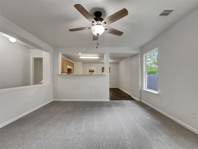 unfurnished living room with dark colored carpet and ceiling fan