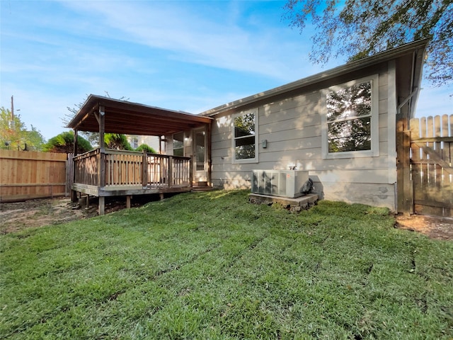 back of property with ac unit, a deck, and a lawn