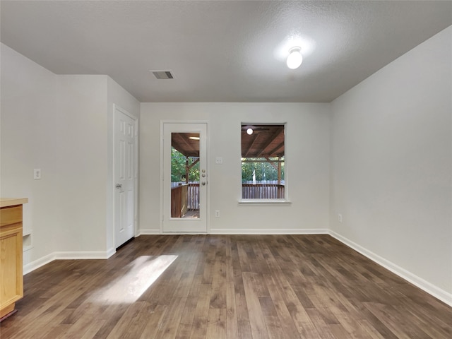 spare room with dark hardwood / wood-style floors and a textured ceiling