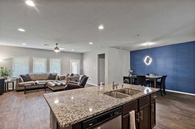 kitchen featuring stainless steel dishwasher, dark wood-type flooring, an island with sink, and pendant lighting