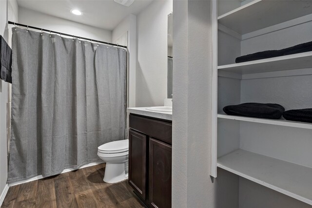 bathroom featuring vanity, hardwood / wood-style floors, walk in shower, and toilet