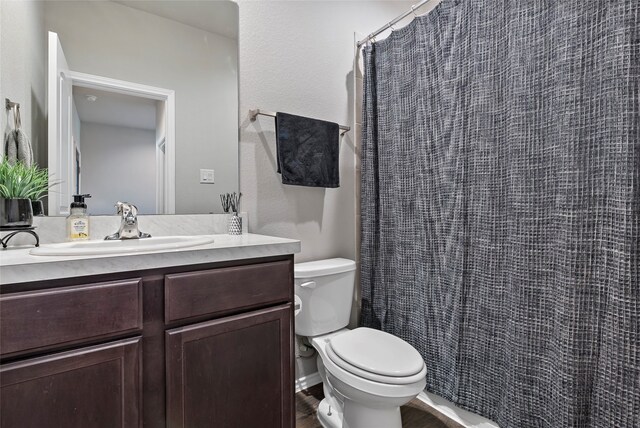 bathroom with toilet, hardwood / wood-style floors, walk in shower, and vanity