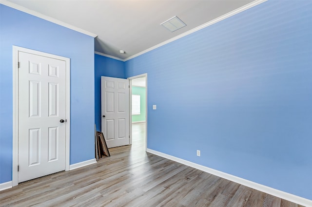 unfurnished bedroom with ornamental molding and light wood-type flooring