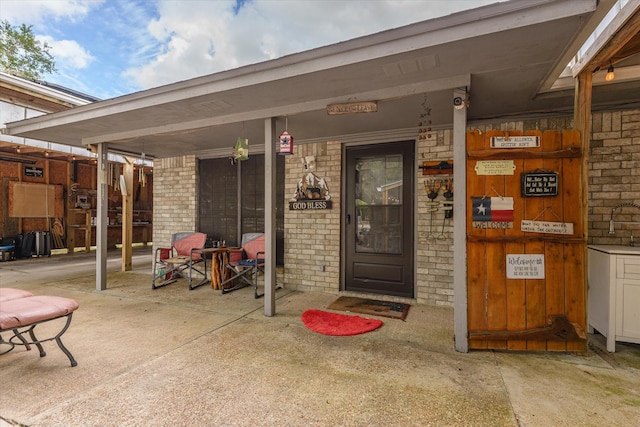 view of exterior entry with a porch and brick siding