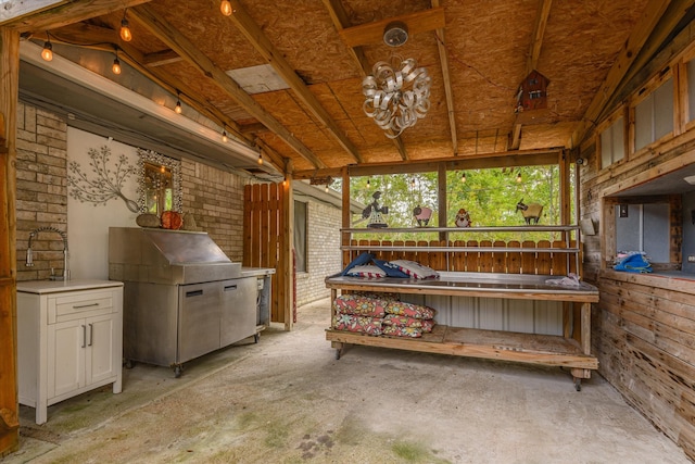 misc room featuring brick wall and vaulted ceiling