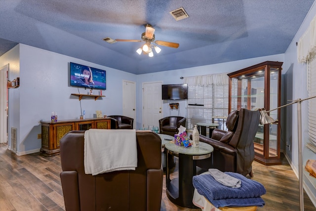 living room featuring a textured ceiling, hardwood / wood-style floors, and ceiling fan