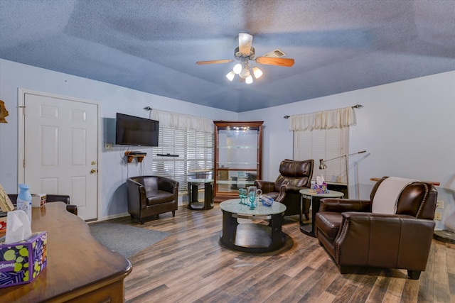 living room with a textured ceiling, ceiling fan, vaulted ceiling, and wood-type flooring