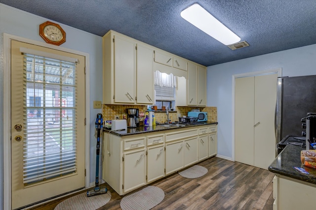 kitchen featuring a textured ceiling, stainless steel fridge, plenty of natural light, and decorative backsplash