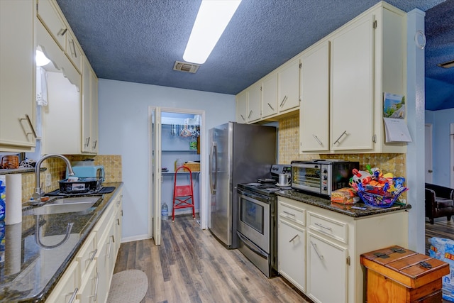 kitchen with stainless steel appliances, tasteful backsplash, white cabinetry, wood-type flooring, and sink