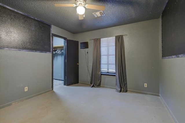 spare room featuring baseboards, visible vents, a ceiling fan, and a textured ceiling
