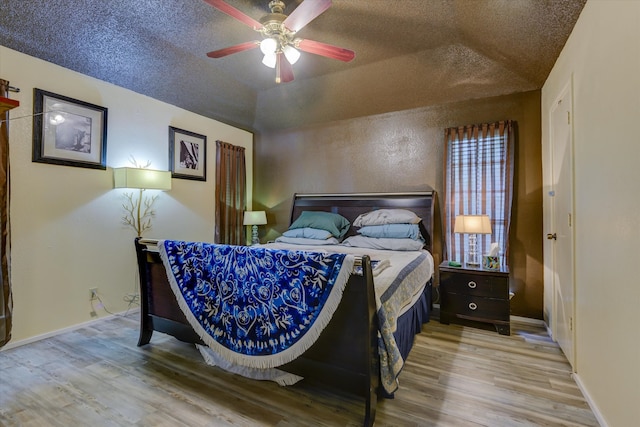 bedroom featuring lofted ceiling, a textured ceiling, ceiling fan, and hardwood / wood-style floors