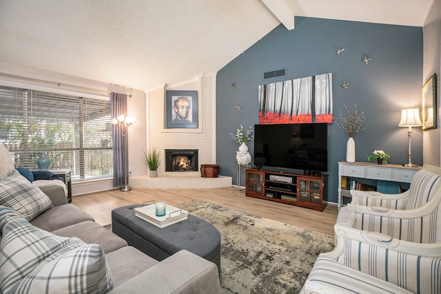 living room with lofted ceiling with beams, a textured ceiling, a fireplace, and hardwood / wood-style floors