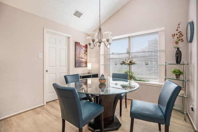 dining area with vaulted ceiling, a notable chandelier, a textured ceiling, and light hardwood / wood-style floors