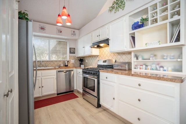 kitchen featuring appliances with stainless steel finishes, light wood-type flooring, hanging light fixtures, white cabinetry, and decorative backsplash