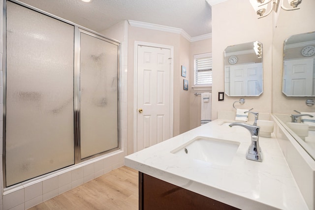 bathroom with a textured ceiling, walk in shower, vanity, hardwood / wood-style flooring, and ornamental molding