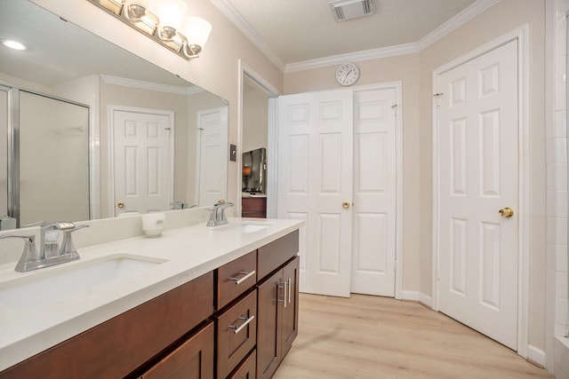 bathroom with hardwood / wood-style floors, crown molding, vanity, a textured ceiling, and an enclosed shower