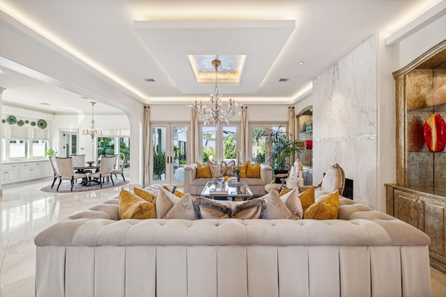 living room featuring french doors, a notable chandelier, and a tray ceiling