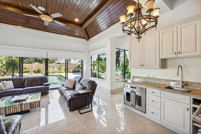 interior space featuring vaulted ceiling, wooden ceiling, sink, and ceiling fan with notable chandelier