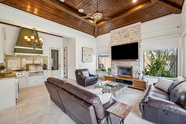 living room featuring ceiling fan with notable chandelier, wood ceiling, a fireplace, and high vaulted ceiling