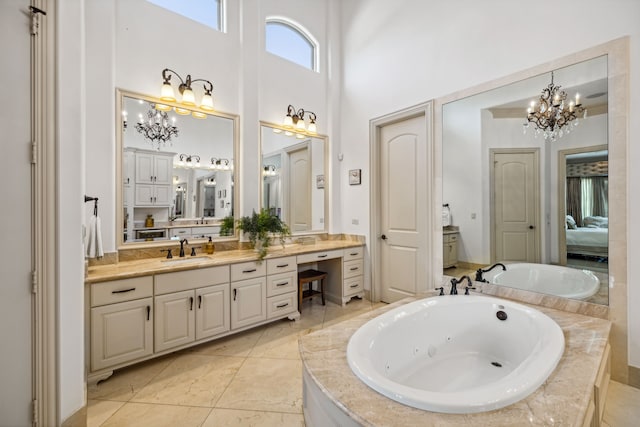 bathroom featuring tile patterned floors, a relaxing tiled tub, an inviting chandelier, vanity, and a towering ceiling