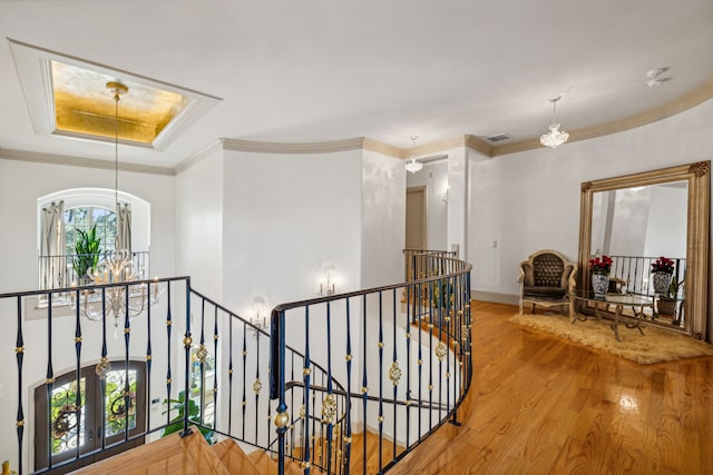 corridor featuring ornamental molding, a notable chandelier, and hardwood / wood-style floors