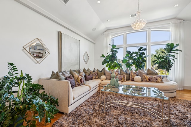 living room featuring vaulted ceiling, wood-type flooring, and an inviting chandelier