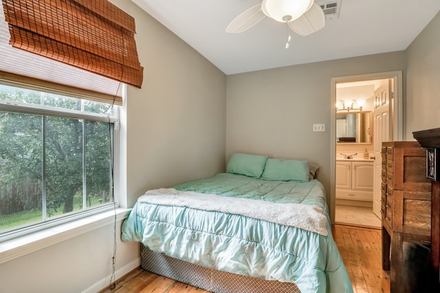 bedroom with ensuite bathroom, light wood-type flooring, and ceiling fan