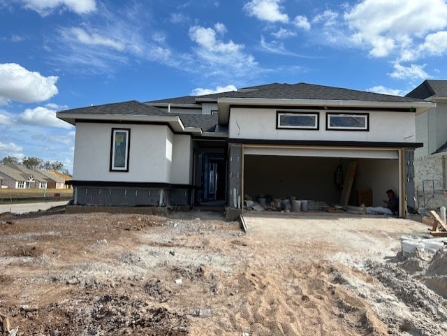 view of front of property with driveway, a garage, stucco siding, and roof with shingles