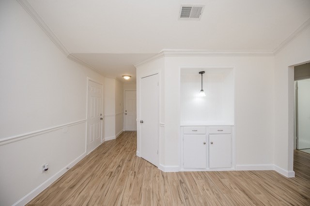 interior space with crown molding and light wood-type flooring