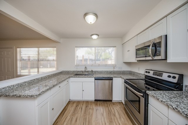 kitchen with sink, white cabinetry, stainless steel appliances, and light wood-type flooring