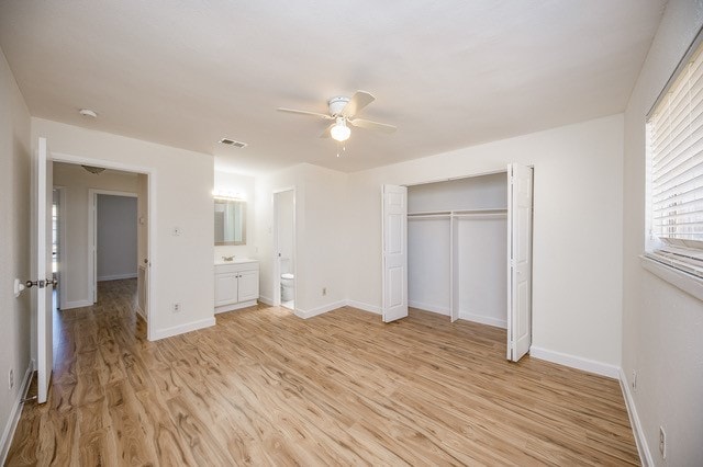 unfurnished bedroom with connected bathroom, light hardwood / wood-style floors, a closet, and ceiling fan