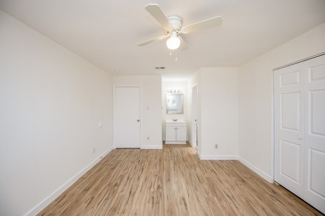 unfurnished bedroom featuring connected bathroom, ceiling fan, a closet, and light hardwood / wood-style flooring