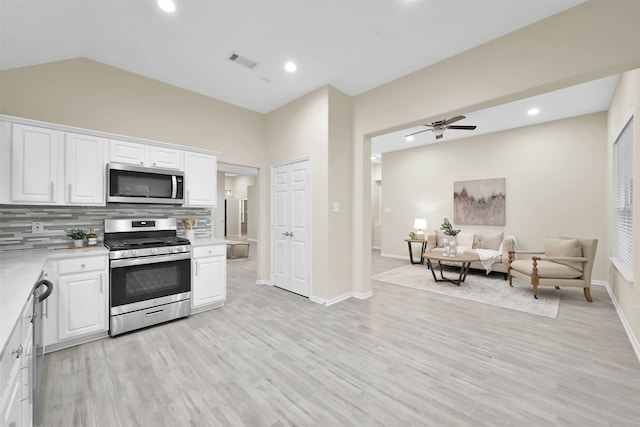 kitchen with white cabinetry, backsplash, appliances with stainless steel finishes, and light hardwood / wood-style flooring