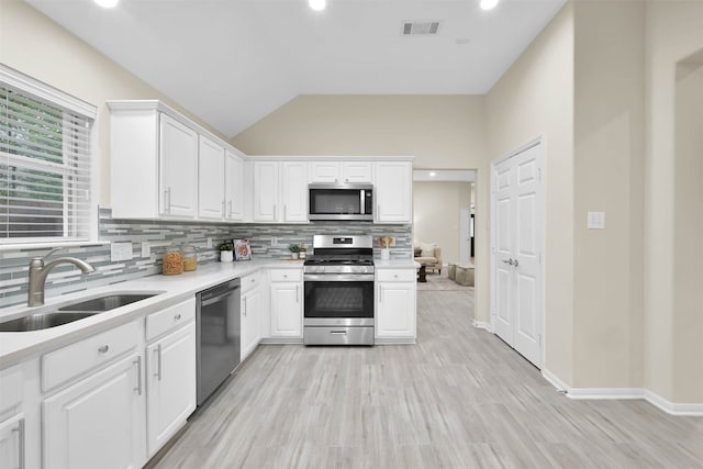 kitchen featuring sink, appliances with stainless steel finishes, white cabinets, and vaulted ceiling