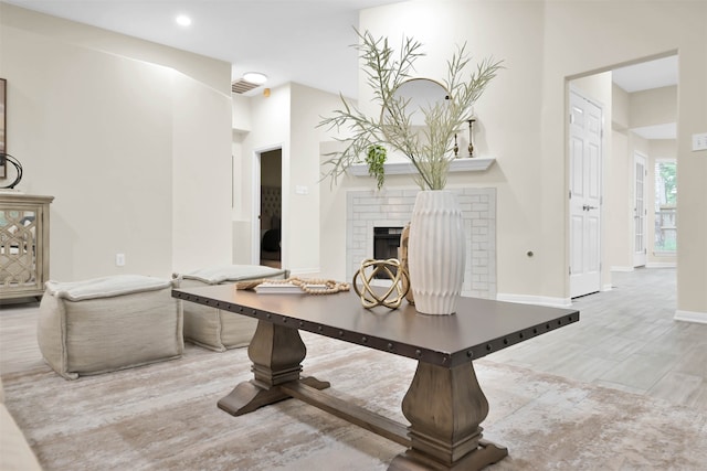 dining space featuring light wood-type flooring and a brick fireplace