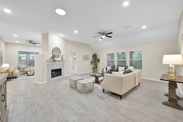 living room with light hardwood / wood-style floors, vaulted ceiling, a fireplace, and ceiling fan