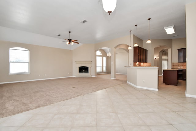 unfurnished living room featuring ceiling fan, light colored carpet, and vaulted ceiling