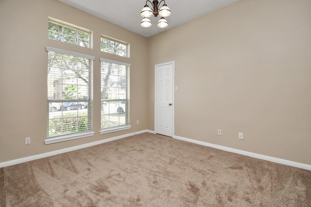 carpeted empty room featuring a notable chandelier