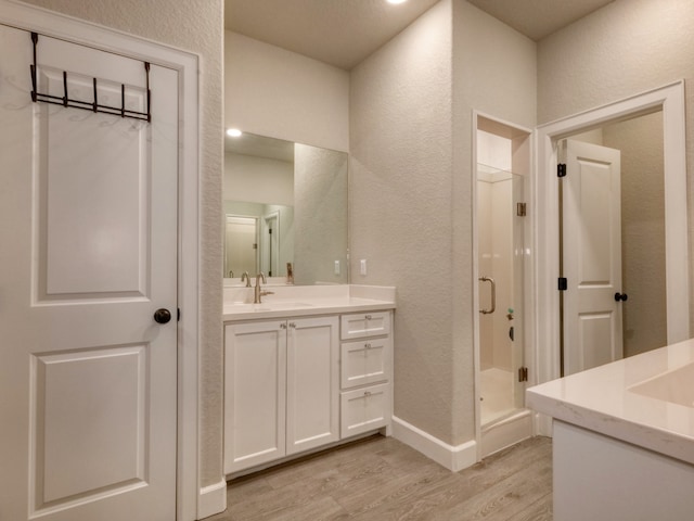 bathroom with a shower with door, vanity, and wood-type flooring